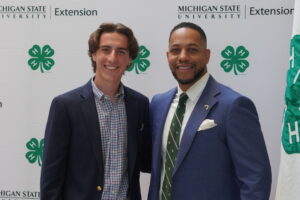 A young man in a blue suit jacket standing next to a man in blue suit jacket.