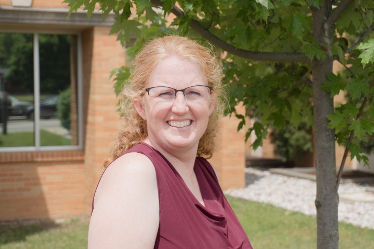A white, red haired female with glasses and a maroon shirt.