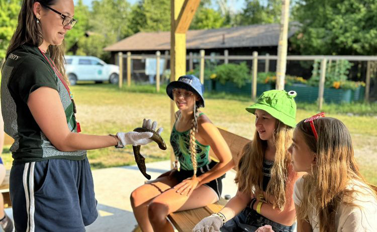 A teacher showing an invasive specie that can be a human challenge as an ecological one, campers discover.